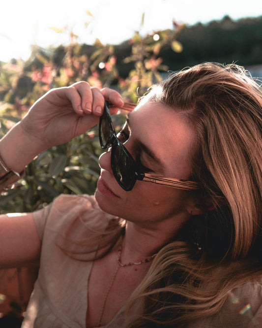 Femme ajustant ses lunettes de soleil en bois The Wood Stock