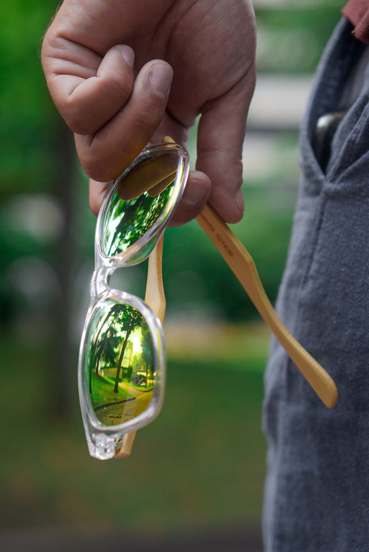 Lunettes de soleil en bois à verres verts tenues à la main