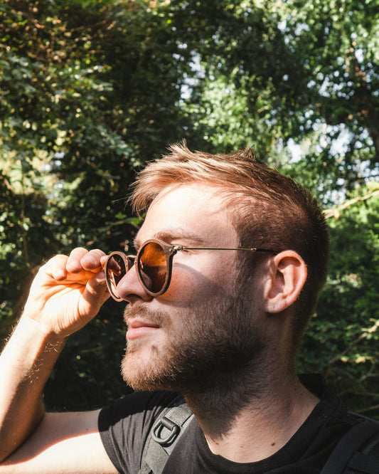 Homme portant des lunettes de soleil rondes en bois The Wood Stock