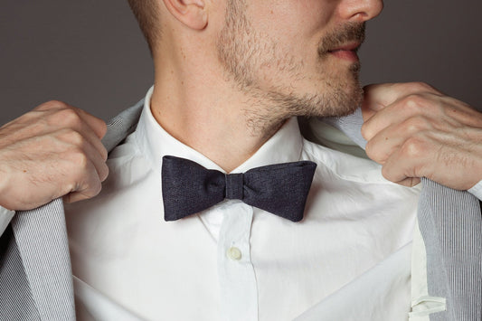 Nœud papillon noué sur une chemise blanche à col classique, sous une veste rayée