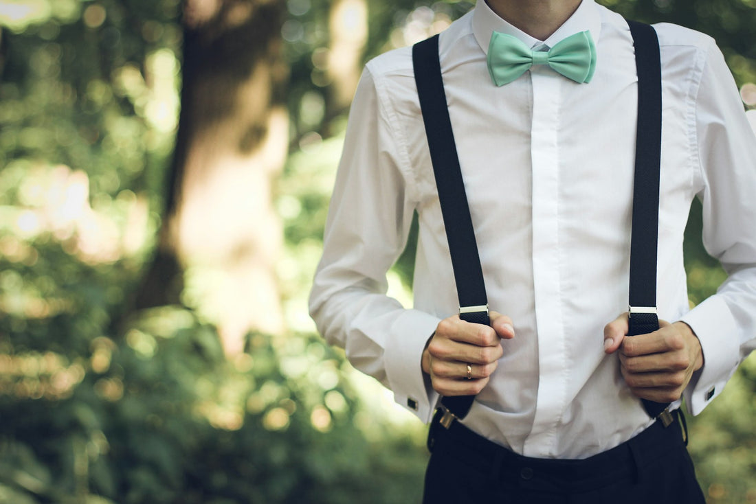 Nœud papillon vert d'eau et bretelles noires sur une chemise blanche, en extérieur