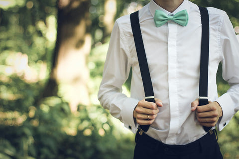 Nœud papillon vert d'eau et bretelles noires sur une chemise blanche, en extérieur
